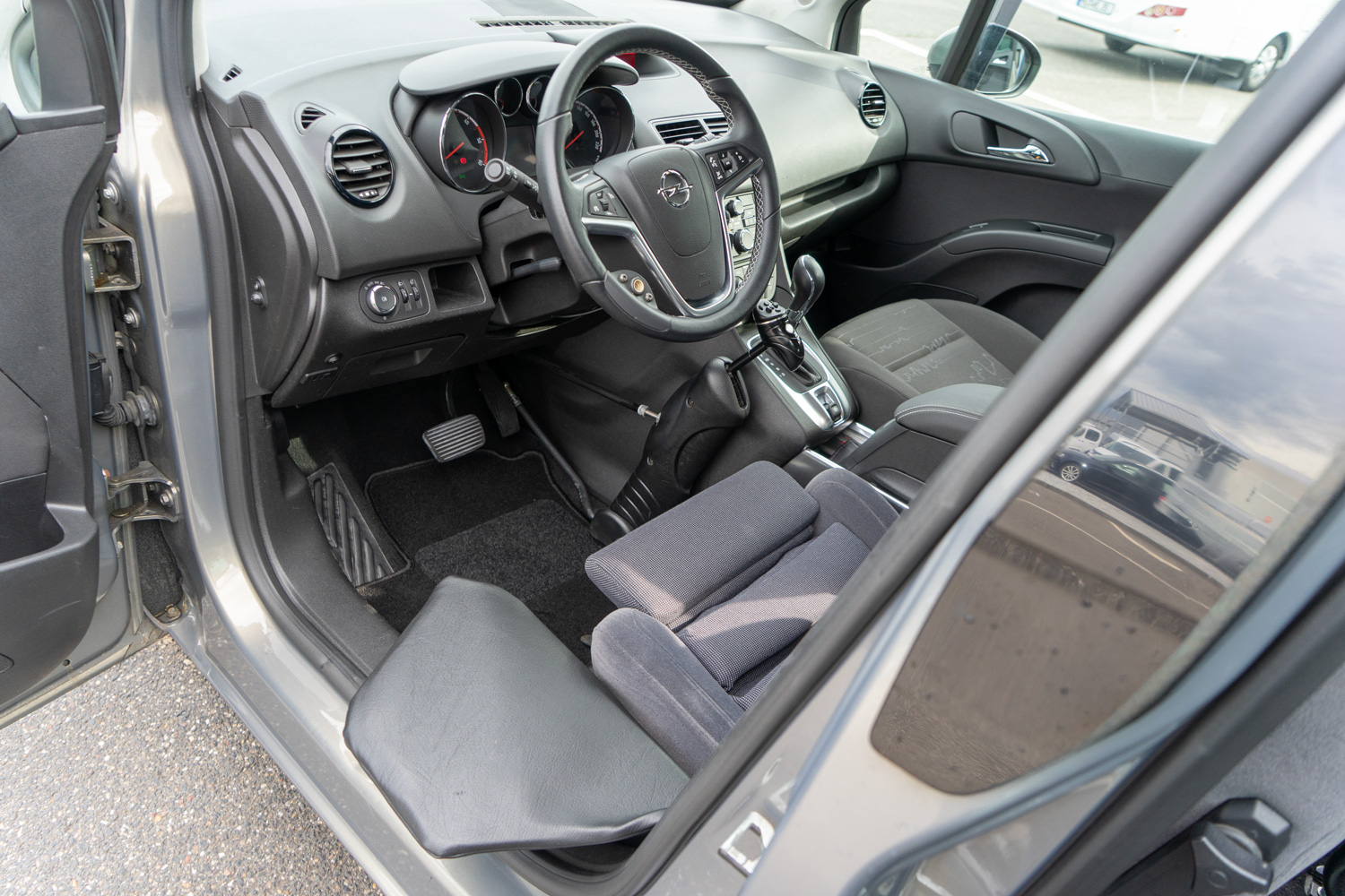 Behindertengerechter Opel Meriva Gebrauchtwagen für Selbstfahrer mit Handicap, Cockpit schräg, Einstiegshilfe Rutschbrett, Lenkraddrehknauf, Handgerät