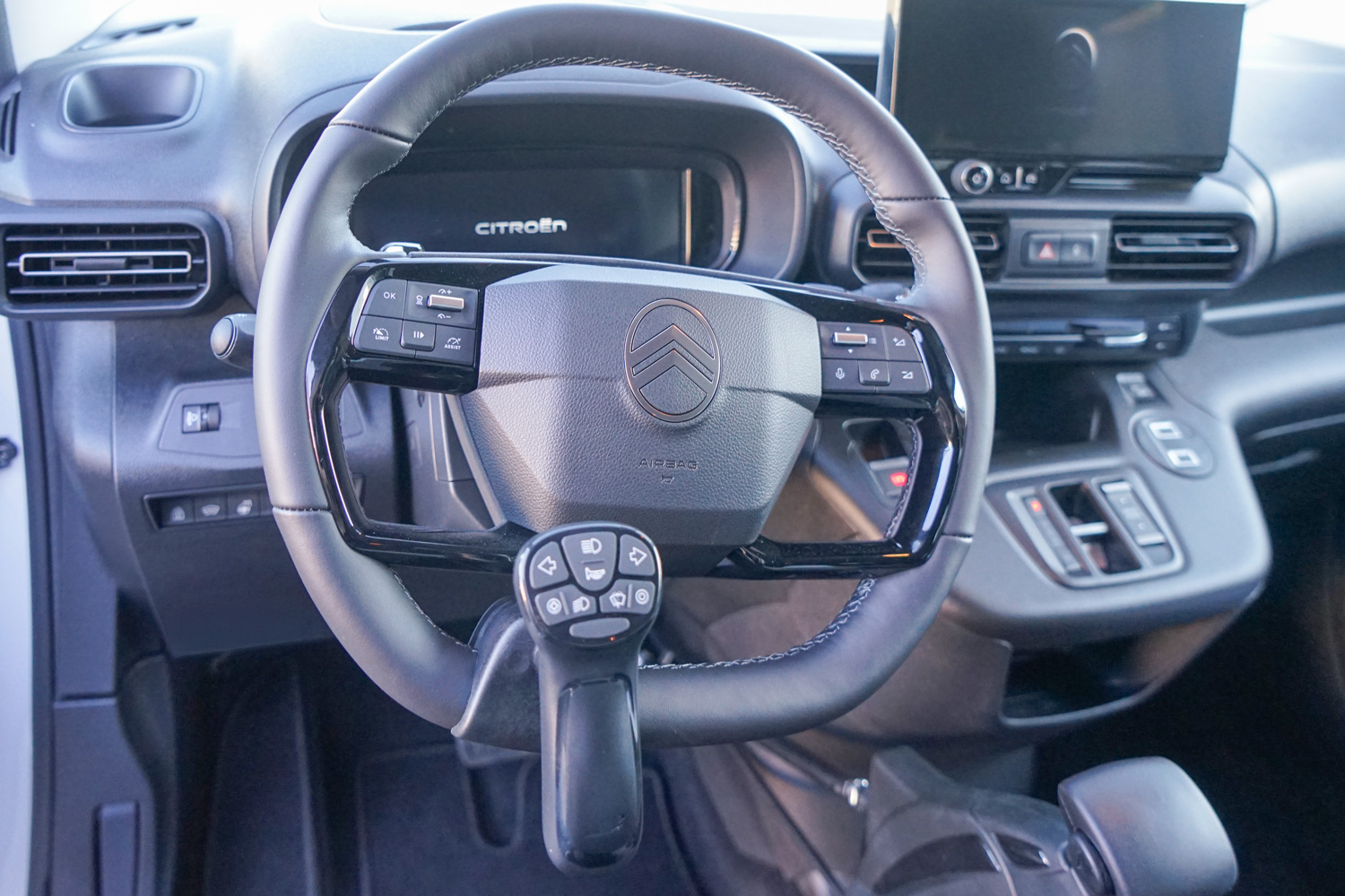 Frontansicht eines Multifunktionslenkraddrehknaufs und Handgeräts für Gas und Bremse in einem behindertengerechten Citroen Berlingo